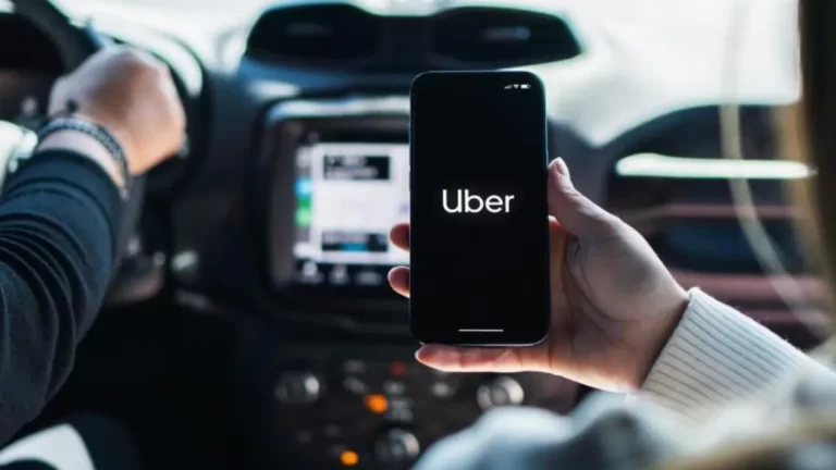 Chica dentro de un coche con un smartphone con la app de Uber en la pantalla. (SHUTTERSTOCK)